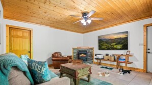 A cozy living room with a fireplace, a sofa, a dog, and a painting on the wall. - Luxury Cabin for Riders Hikers & Anglers +Hot Tub (Pisgah Forest)
