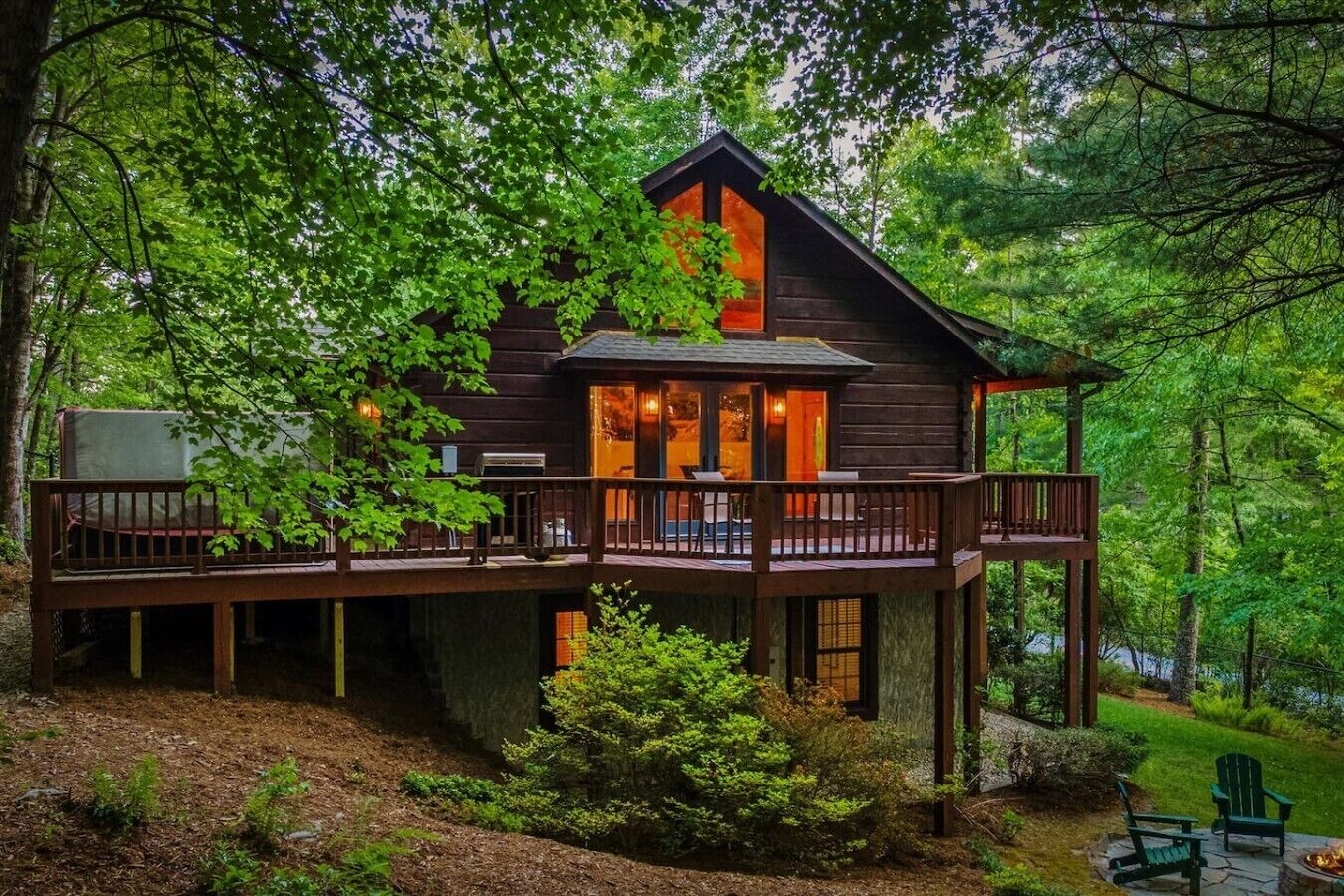 A cabin with a deck, surrounded by trees.
