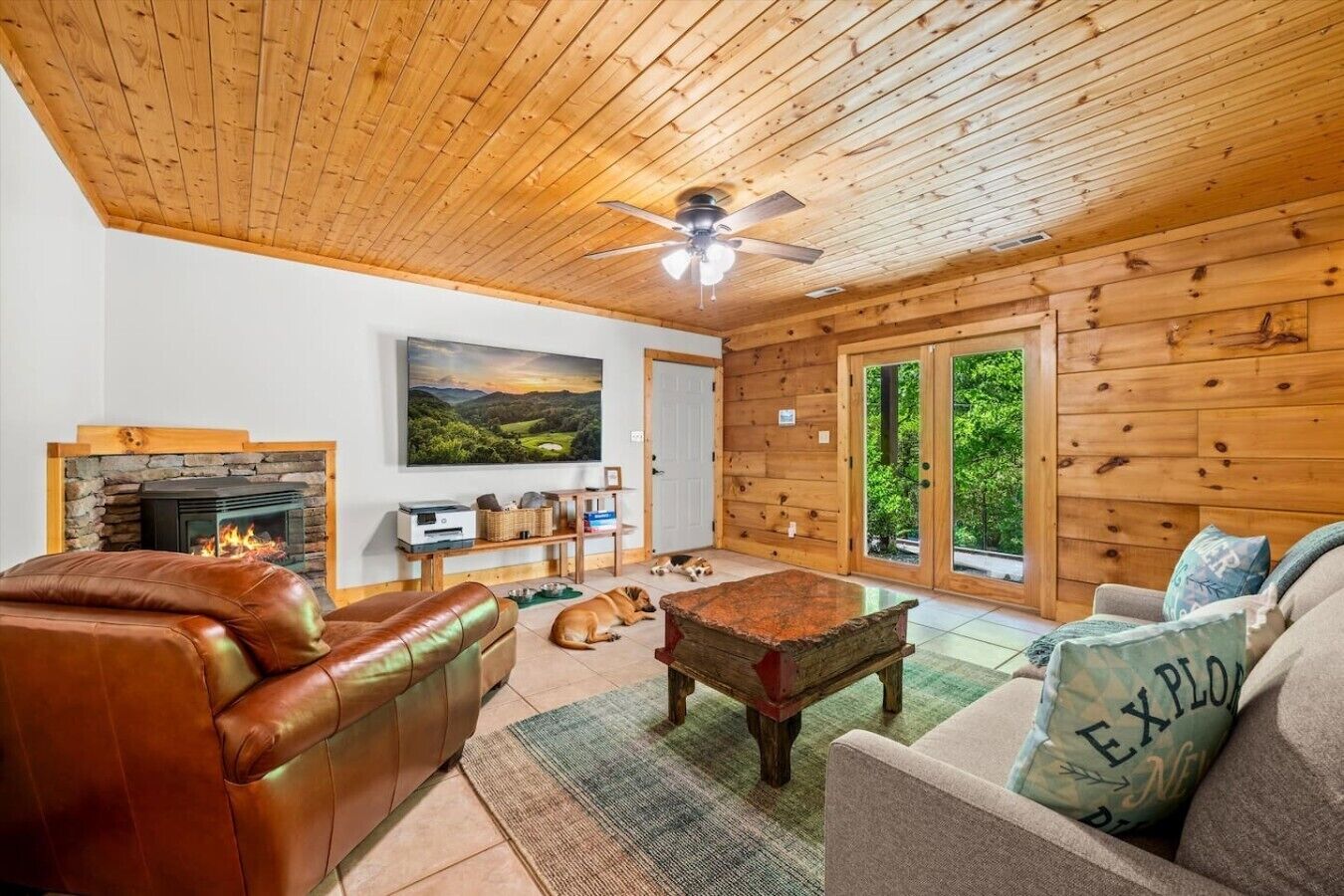 A cozy living room with a fireplace, leather sofas, a coffee table, and a dog.