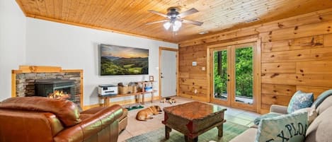 Una sala de estar acogedora con chimenea, sofás de cuero, una mesa de centro y un perro.