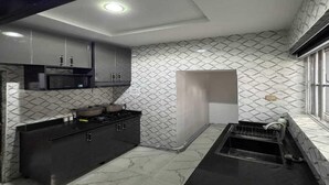 Cocina compacta con microondas, estufa y encimera negra.
