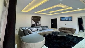 Una sala moderna con un sofá modular, una mesa de centro redonda y una alfombra negra.