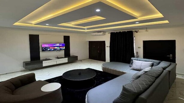 Una sala de estar moderna con un televisor de pantalla plana, un sofá, una mesa de centro e iluminación empotrada en el techo.