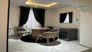 Un comedor moderno con una mesa redonda, cuatro sillas, un refrigerador y un televisor montado en la pared.