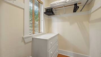 A small, white closet with a window, a radiator, and a shelf above the door.