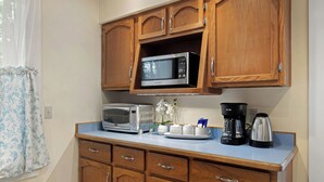 A kitchenette with wooden cabinets, a microwave, a toaster, a coffee maker, and a small plant. - U-District 1 Bedroom Craftsman w/ Fenced Yard (Butte)