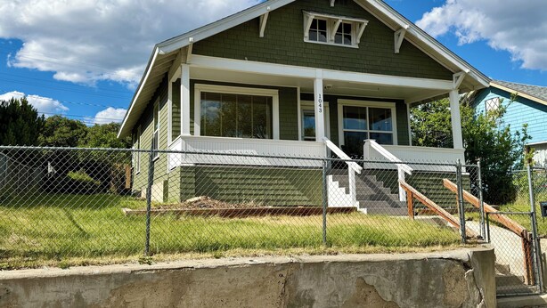 A two-story house with a porch, a front door, and a visible address number. - U-District 1 Bedroom Craftsman w/ Fenced Yard (Butte)