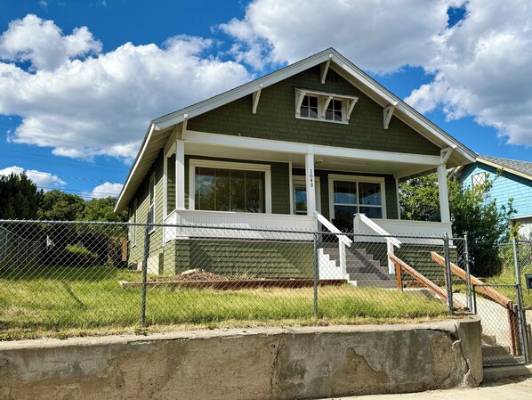 A two-story house with a porch, a front door, and a visible address number.