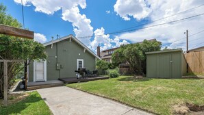 A residential backyard with a patio, a green shed, and a house with a chimney. - U-District 1 Bedroom Craftsman w/ Fenced Yard (Butte)