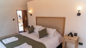 Ein ordentlich bezogenes Bett mit Holz-Kopfteil, zwei Nachttische und eine Tür zu einem Außenbereich.