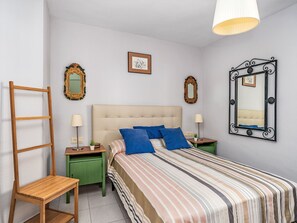Ein Schlafzimmer mit Bett, Nachttischen, einer Holzleiter, einem grünen Schrank und einem Spiegel.