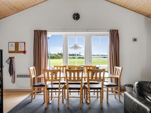 Un comedor con una mesa y sillas, un reloj en la pared y vistas al exterior.