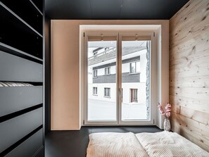 Ein Schlafzimmer mit großem Fenster, einem Bett und einer Holzwand.