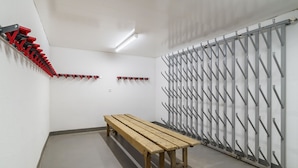 A room with a wooden bench, a red and black coat rack, and a grey metal rack with hooks. - Haus Astoria Appartement/Fewo Apt. # 3 by Interhome (Saas-Grund)