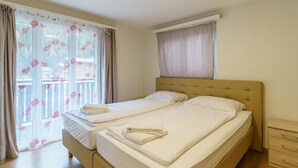 A double bed with a headboard, a bedside table, and a window with curtains. - Haus Astoria Appartement/Fewo Apt. # 3 by Interhome (Saas-Grund)
