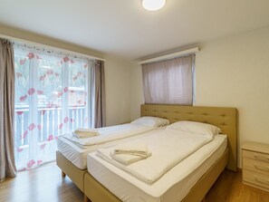 Ein Doppelbett mit Kopfteil, ein Nachttisch und ein Fenster mit Vorhängen.