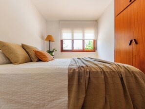 A bedroom with a bed, pillows, a lamp, a window, and a wardrobe. - Vacation home Nuri by Interhome (Deltebre)