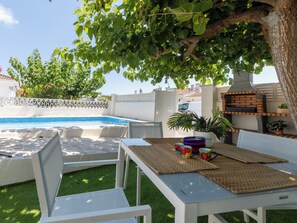 A poolside area with a table, chairs, and a barbecue grill. - Vacation home Nuri by Interhome (Deltebre)
