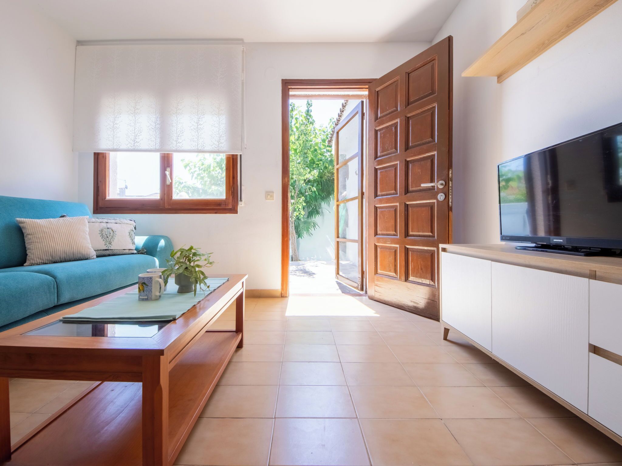 A living room with a sofa, coffee table, TV, and a door leading outside.