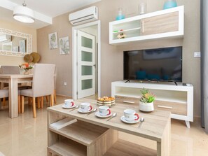 A modern living room with a TV, a dining area, and a white console unit. - Ciudad Jardin II by Interhome (Oropesa del Mar)