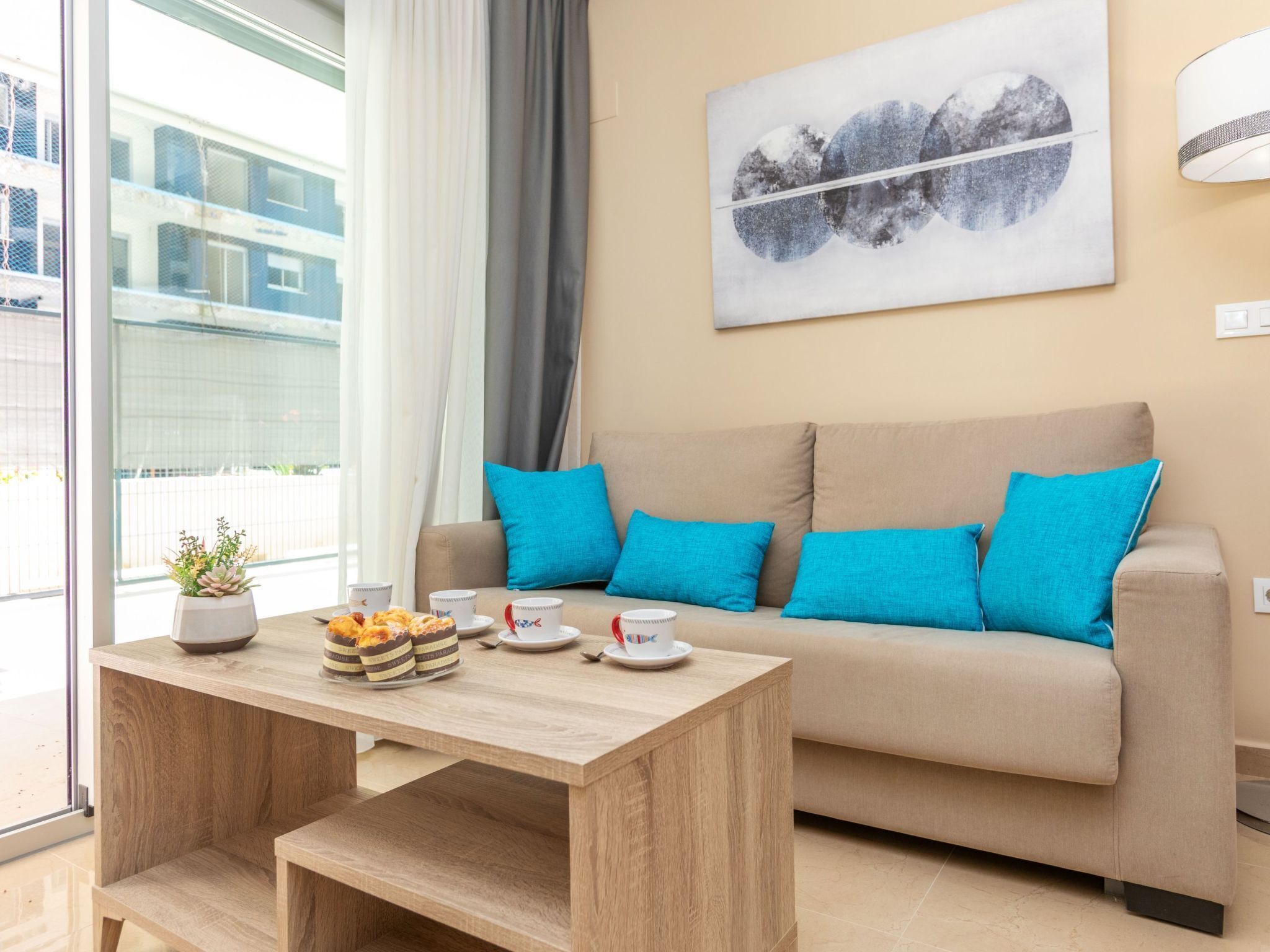A modern living room with a sofa, a coffee table, and a painting on the wall.