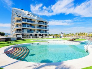 A modern multi-story hotel with a swimming pool and a children's play area. - Ciudad Jardin II by Interhome (Oropesa del Mar)