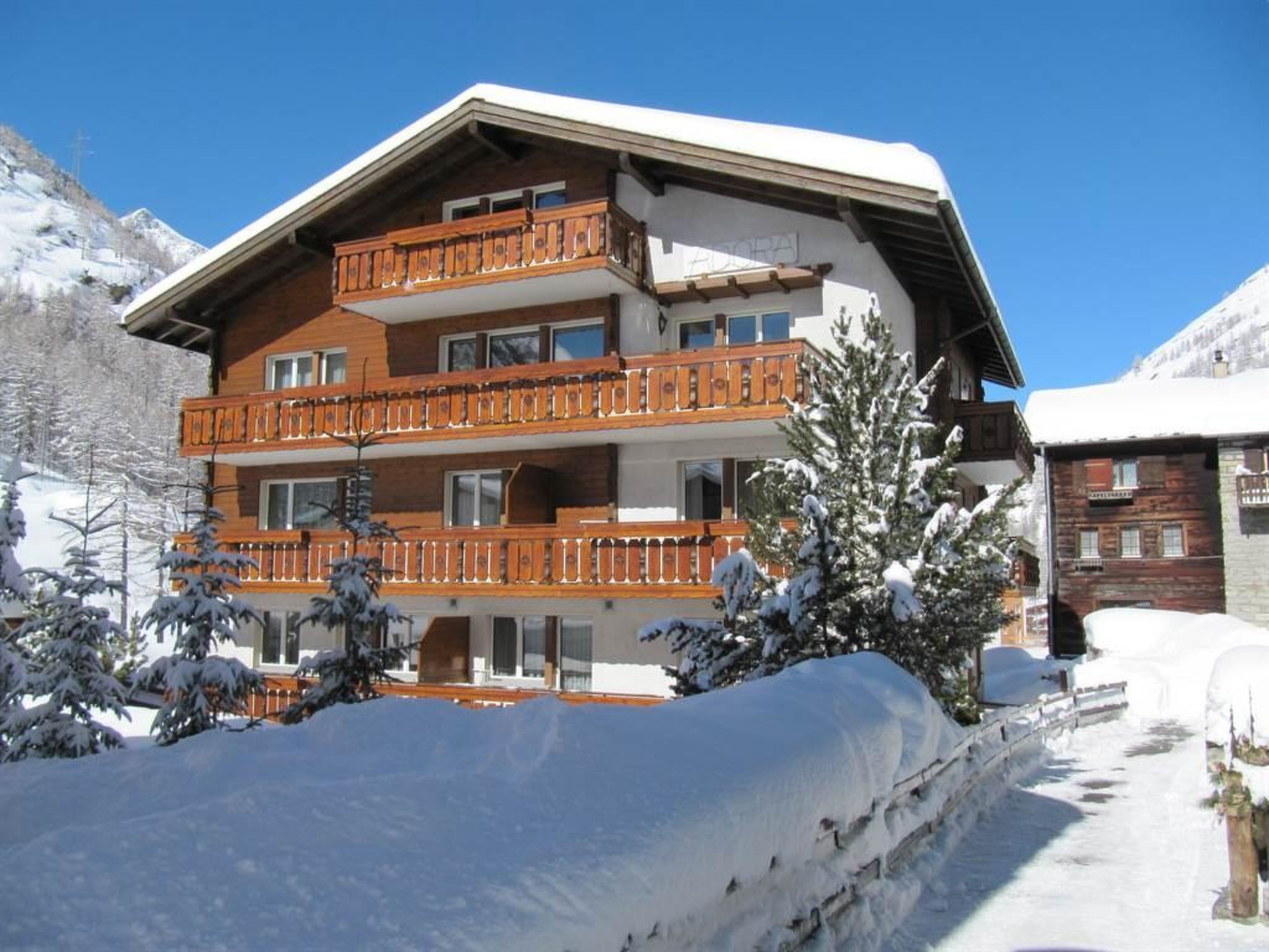 Un hôtel à plusieurs étages, doté de balcons en bois et surplombant un paysage enneigé.
