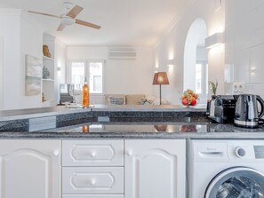 A modern kitchen with a built-in washing machine, a ceiling fan, and a dining area with a table and chairs. - Club Sevilla I by Interhome (Oliva)