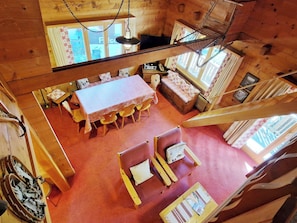 L’intérieur d’un chalet en bois, avec une table à manger, des chaises, un canapé et un escalier.