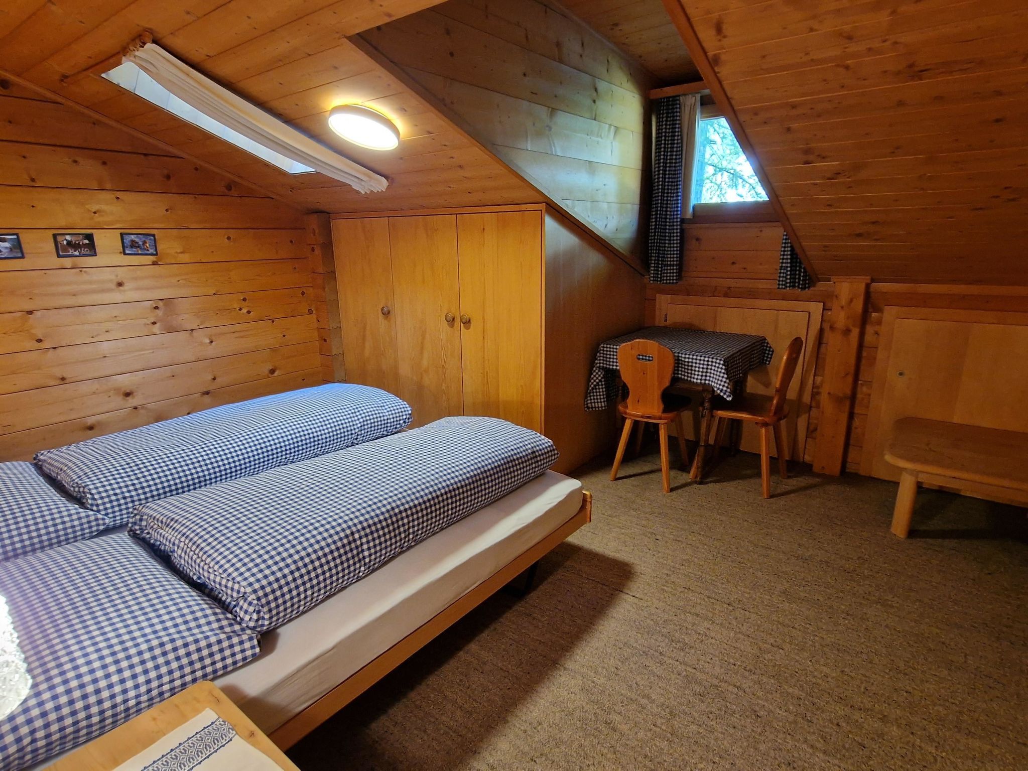 A small, cozy room with a single bed, a table with chairs, and a window with curtains.
