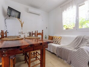 A dining area with a wooden table, chairs, and a TV mounted on the wall. - Vacation home Pepeta by Interhome (Deltebre)