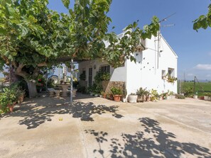 A white building with a garden, potted plants, and a tree providing shade. - Vacation home Pepeta by Interhome (Deltebre)