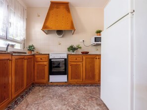 A kitchen with wooden cabinets, a stove, a microwave, and a sink. - Vacation home Pepeta by Interhome (Deltebre)