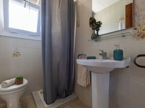 Een badkamer met toilet, douche, wastafel en spiegel.