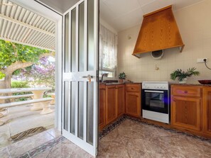 A kitchen with wooden cabinets, a stove, and a dining area with a table and chairs. - Vacation home Pepeta by Interhome (Deltebre)
