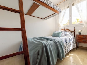 A bedroom with a bed, a nightstand, a window with curtains, and a wooden ceiling structure. - Vacation home Pepeta by Interhome (Deltebre)