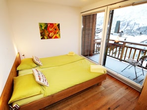 A room with a bed, pillows, a painting, and a balcony with a view. - Symbiose Appartement/Fewo, Dusche und Bad, WC, 3 Schlafräume by Interhome (Saas-Fee)
