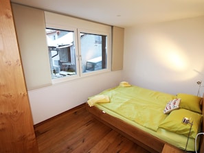 A small room with a single bed, a window, and a wooden floor. - Symbiose Appartement/Fewo, Dusche und Bad, WC, 3 Schlafräume by Interhome (Saas-Fee)