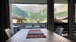 Une table à manger avec des chaises, une vue sur un paysage montagneux et une terrasse en bois.