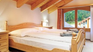 Ein hölzernes Bett in einem Zimmer mit Blick auf eine Berglandschaft durch ein großes Fenster.