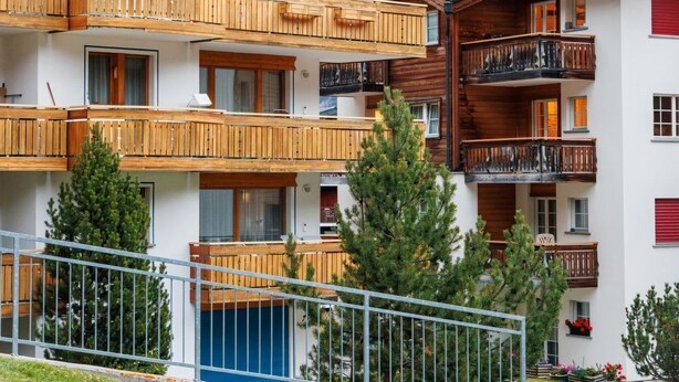 Ein mehrstöckiges Hotel mit hölzernen Balkonen und Blick auf die Berge.