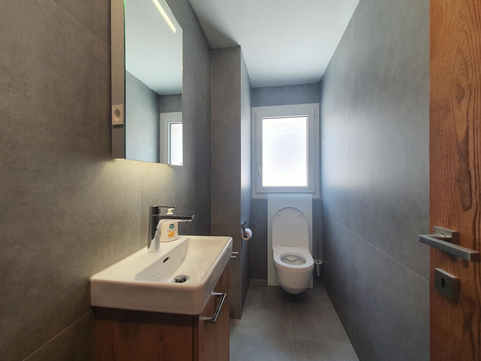 A modern bathroom with a sink, mirror, and toilet.