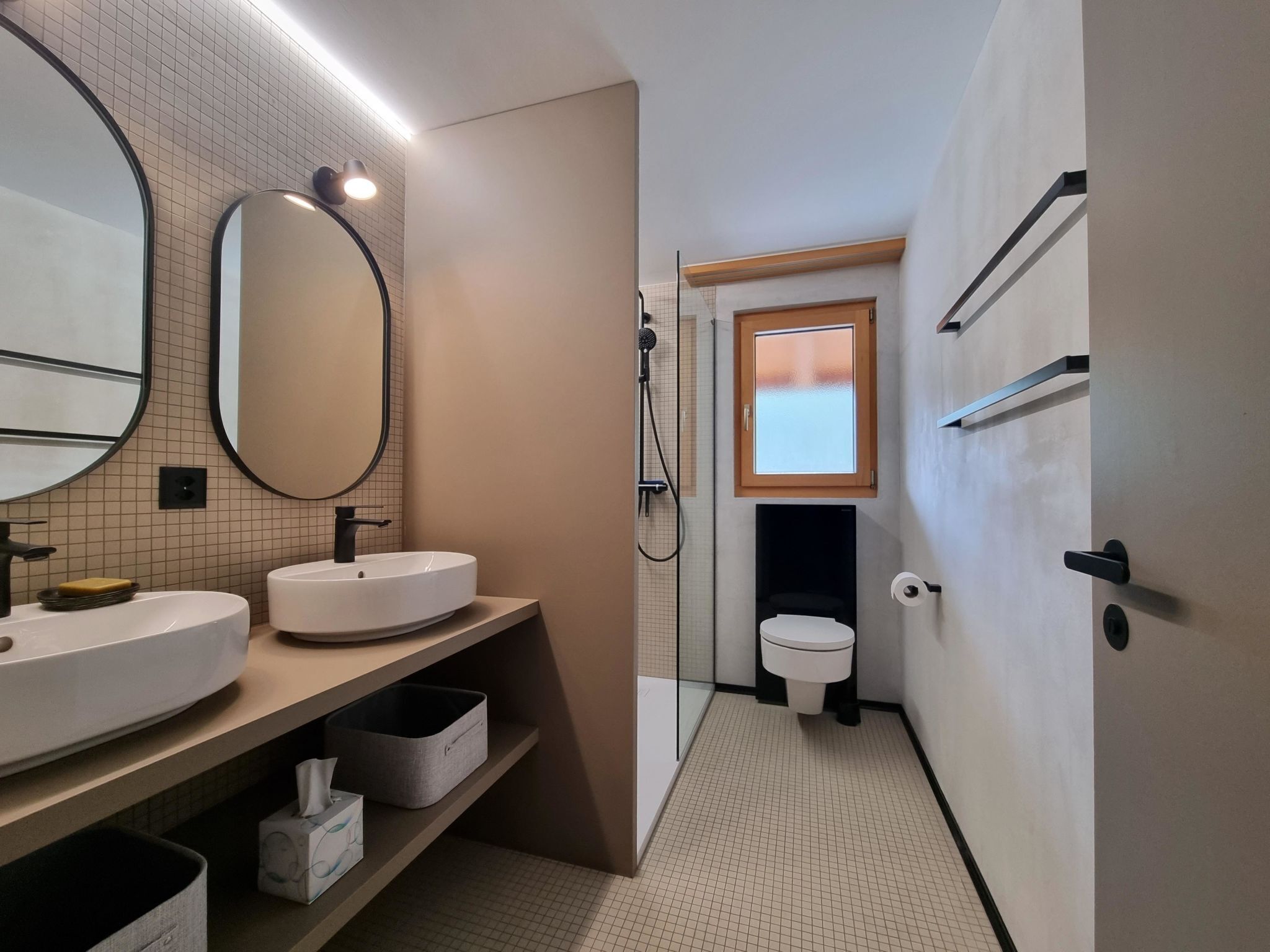 A modern bathroom with two sinks, a mirror, a toilet, and a shower.