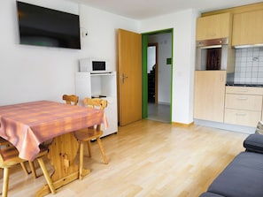 A compact living space with a dining table, chairs, a microwave, and a kitchenette. - Apartments Atlas Appartement/Fewo Atlas 3 by Interhome (Saas-Grund)