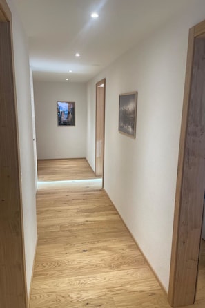 A hallway with wooden flooring, white walls, and two framed pictures. - Alphubel Peak & Unlimited Appartement/Fewo Peak 03 by Interhome (Saas-Fee)