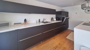 Eine moderne Küche mit dunklen Schränken, einer weißen Arbeitsplatte und einem eingebauten Backofen.