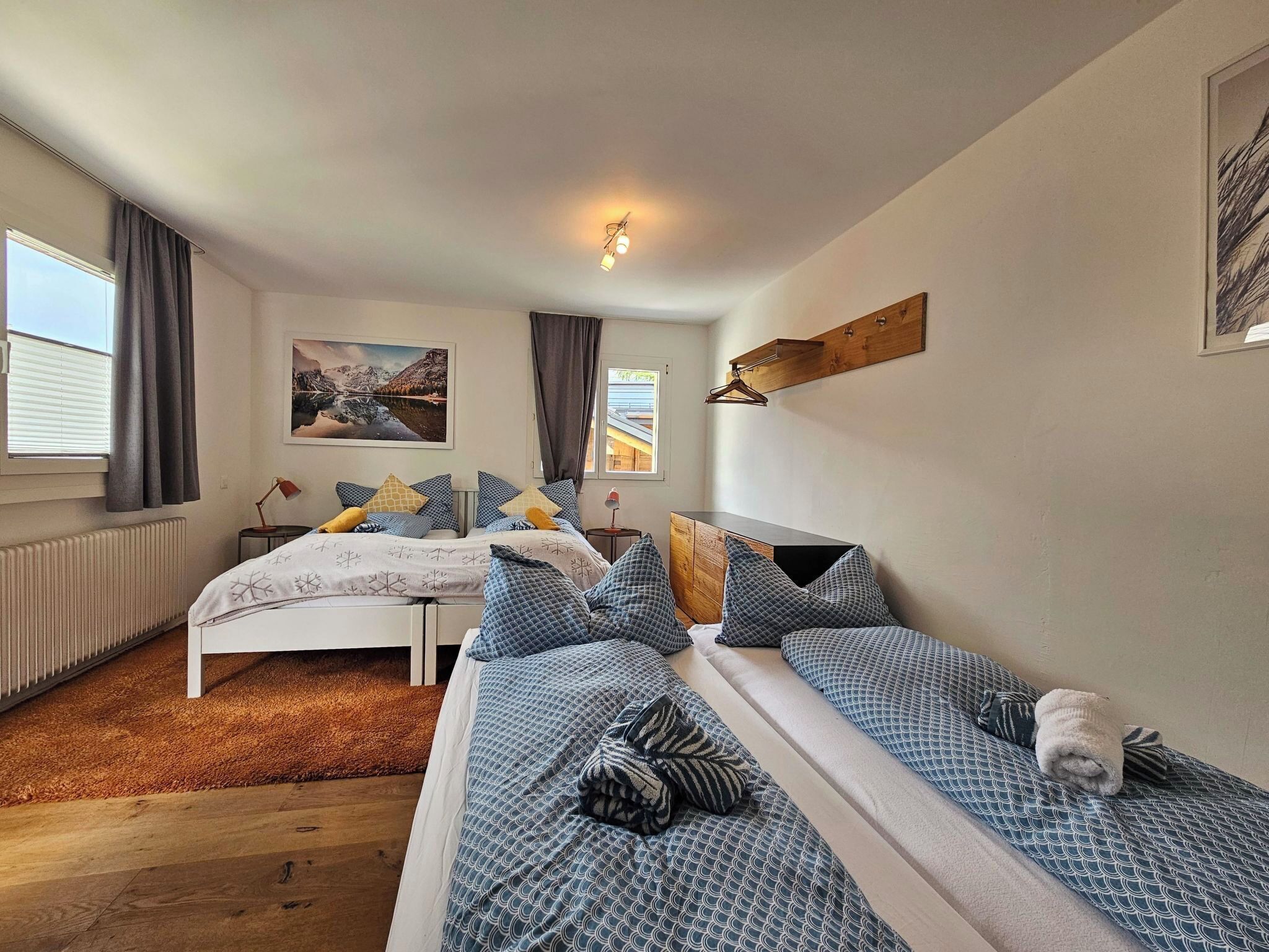 Ein Schlafzimmer mit zwei Betten, einem Heizkörper, einer Pendelleuchte und einem Bild an der Wand.
