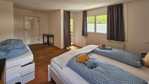 Ein Schlafzimmer mit zwei Betten, einem kleinen Tisch, einem Heizkörper und einer Tür.