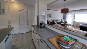 Cozinha moderna com armários brancos, geladeira embutida e bancada de madeira com utensílios de cozinha.