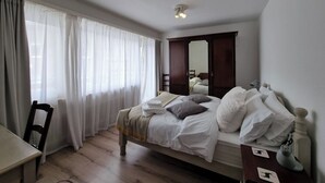 Quarto com cama, cadeira, escrivaninha, guarda-roupa e espelho.